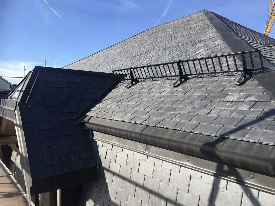 Extérieur résidentiel avec toitures en ardoise naturelle grise sous ciel bleu
