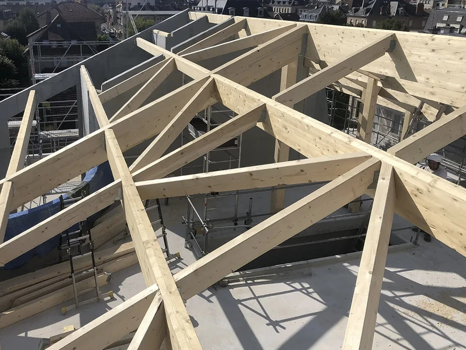 Chantier de construction résidentielle en extérieur sous ciel bleu, charpente en bois en cours d'assemblage sans présence humaine visible
