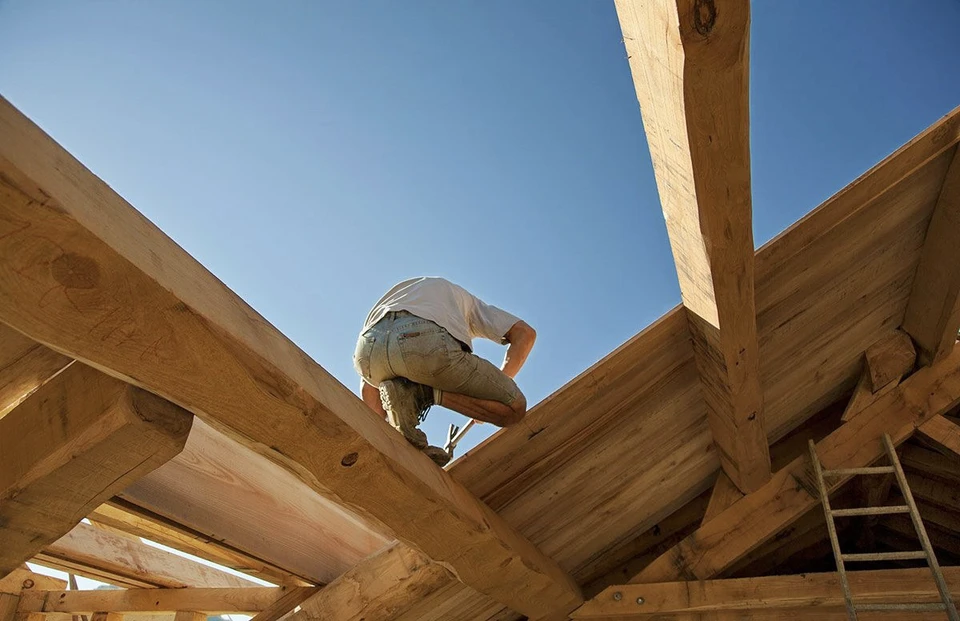 Ouvrier en bâtiment consulte des plans sur chantier de construction à ossature bois