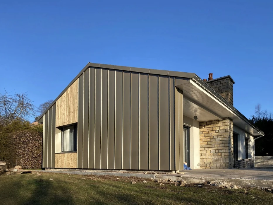 Façade de cathédrale gothique en grès rouge avec deux tours asymétriques, portail à colonnes sculptées sous ciel bleu